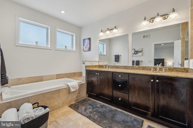 bathroom featuring tile patterned floors, vanity, and tiled bath