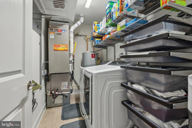 clothes washing area featuring heating unit, washing machine and dryer, and water heater