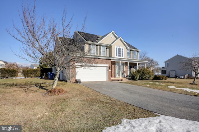 view of front of house featuring a garage, a porch, a front yard, and solar panels