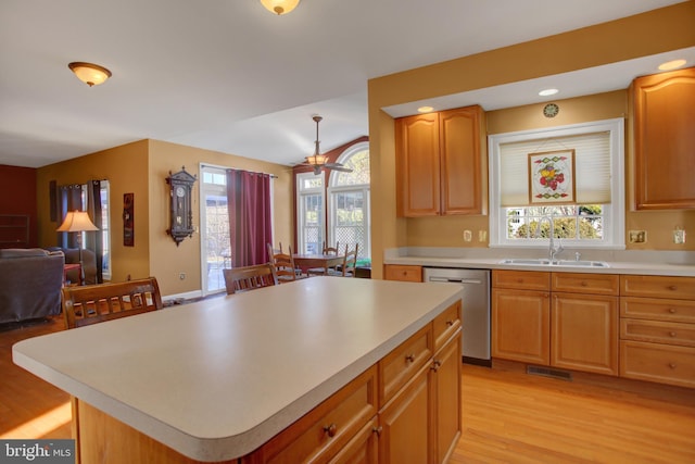 kitchen featuring sink, a center island, vaulted ceiling, stainless steel dishwasher, and light hardwood / wood-style floors