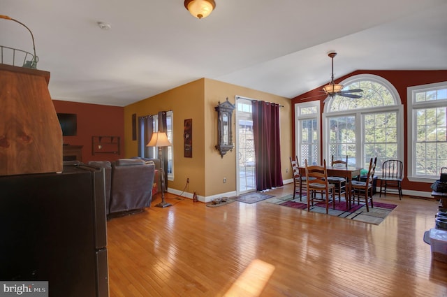 dining space with ceiling fan, lofted ceiling, and light hardwood / wood-style flooring