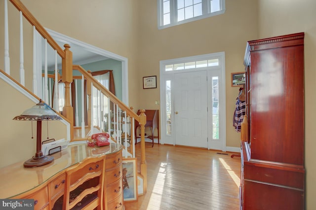 entrance foyer with a towering ceiling and light wood-type flooring