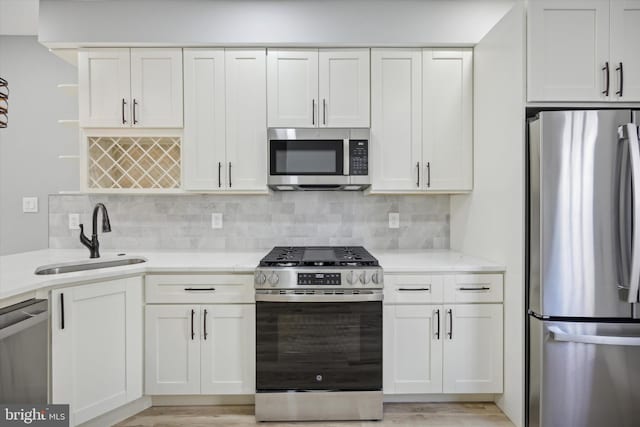 kitchen with stainless steel appliances, white cabinetry, sink, and backsplash