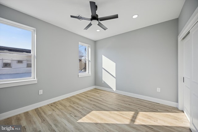 unfurnished bedroom with multiple windows, light hardwood / wood-style flooring, ceiling fan, and a closet