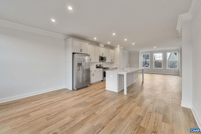 kitchen with appliances with stainless steel finishes, white cabinetry, sink, a kitchen island with sink, and crown molding