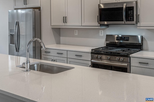 kitchen with appliances with stainless steel finishes, sink, and gray cabinetry