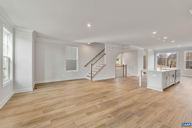 unfurnished living room featuring a healthy amount of sunlight, ornamental molding, and light hardwood / wood-style flooring