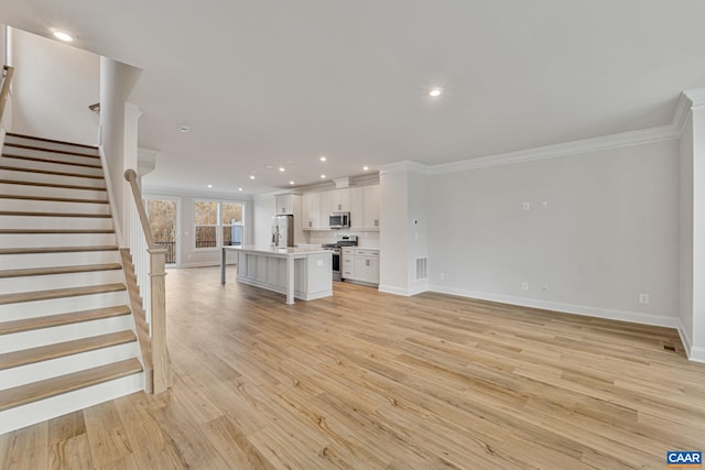 unfurnished living room featuring ornamental molding and light wood-type flooring