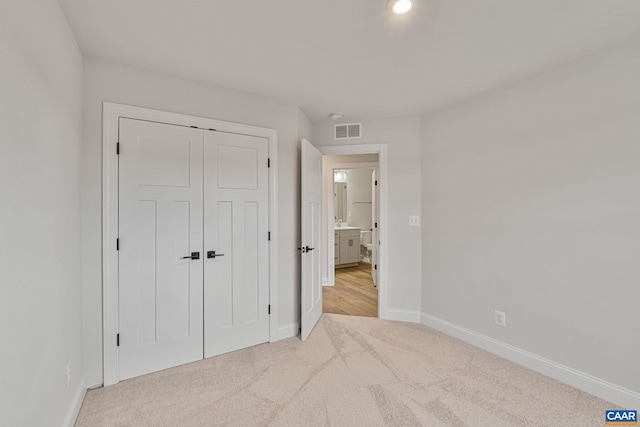 unfurnished bedroom featuring light colored carpet and a closet