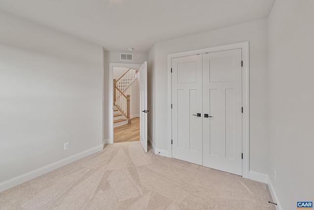 unfurnished bedroom with light carpet and a closet