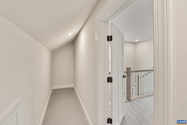 hallway with light colored carpet and vaulted ceiling