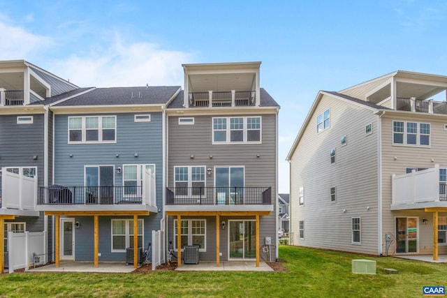 rear view of property with a lawn, a patio, and central air condition unit