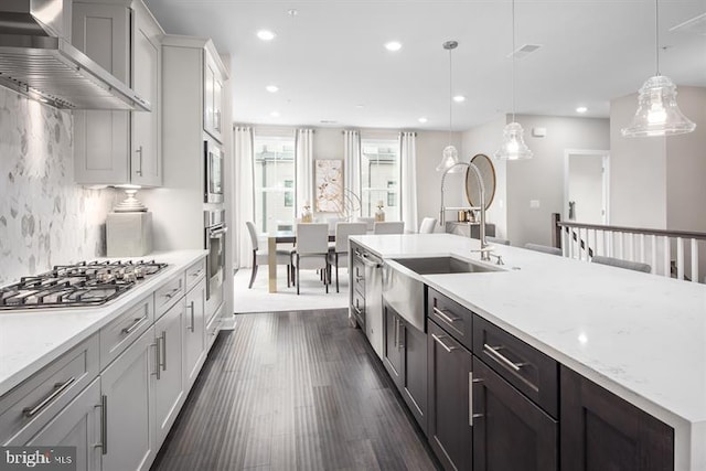 kitchen featuring wall chimney exhaust hood, pendant lighting, stainless steel appliances, light stone countertops, and backsplash