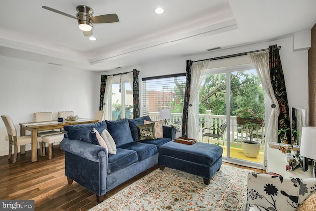 living room featuring ceiling fan, dark hardwood / wood-style floors, and a raised ceiling