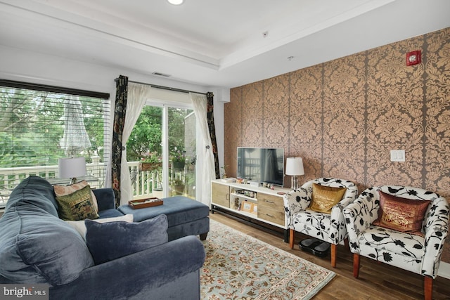 living room featuring a raised ceiling and dark hardwood / wood-style flooring