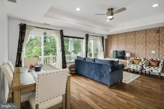 living room featuring a raised ceiling, hardwood / wood-style floors, and ceiling fan