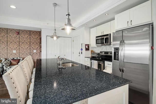 kitchen featuring white cabinetry, appliances with stainless steel finishes, sink, and an island with sink