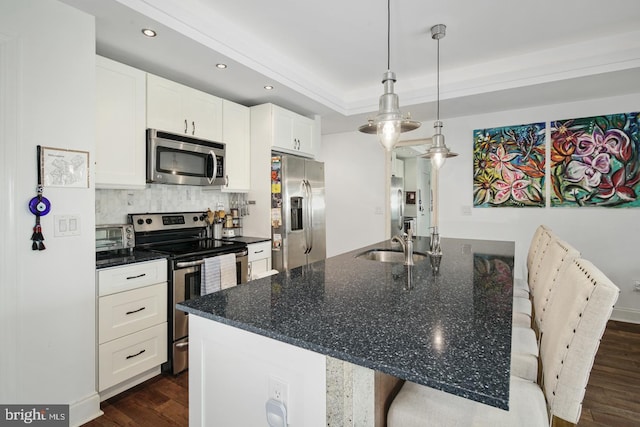 kitchen with sink, a breakfast bar area, hanging light fixtures, stainless steel appliances, and white cabinets