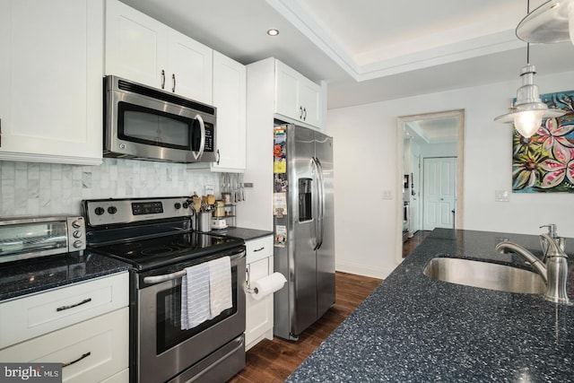 kitchen with sink, white cabinetry, decorative light fixtures, appliances with stainless steel finishes, and backsplash