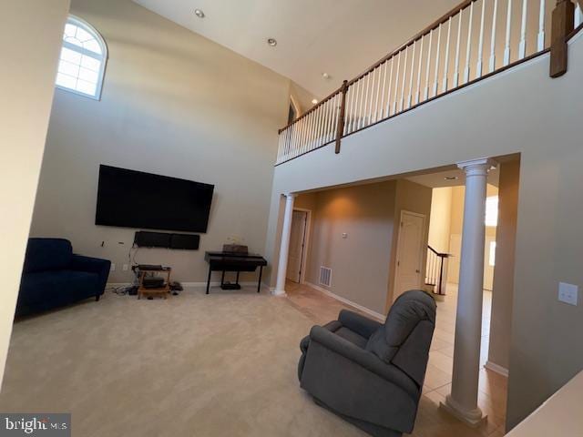 living room featuring carpet flooring, a towering ceiling, and ornate columns