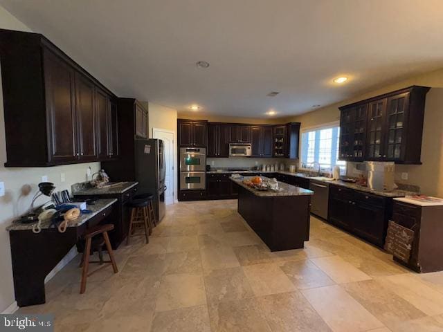 kitchen featuring dark brown cabinets, stainless steel appliances, a breakfast bar area, and a kitchen island