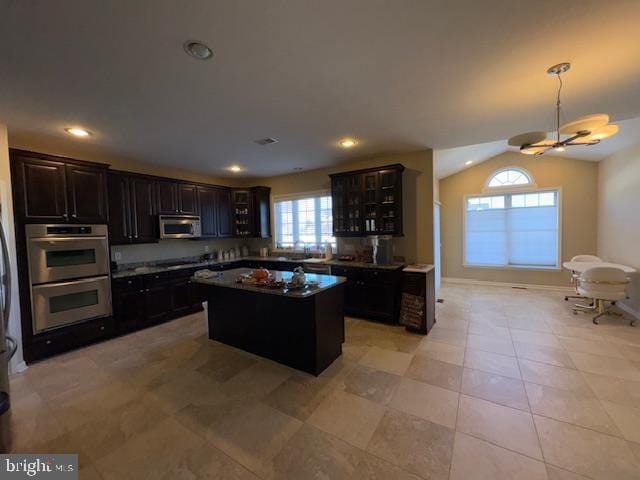 kitchen featuring a kitchen island, appliances with stainless steel finishes, dark brown cabinets, and lofted ceiling