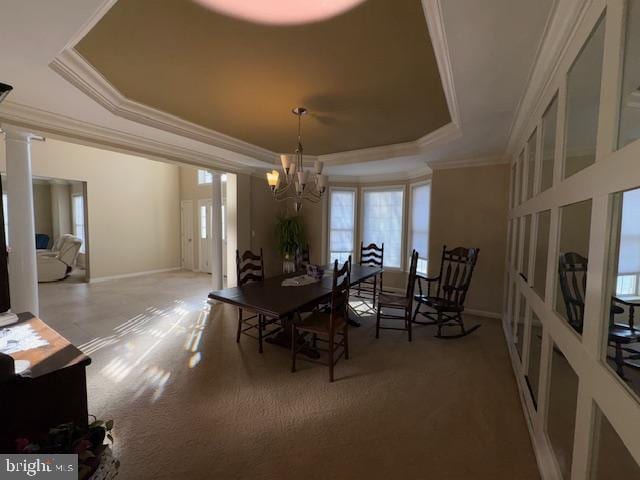 dining space featuring an inviting chandelier, a tray ceiling, crown molding, and ornate columns