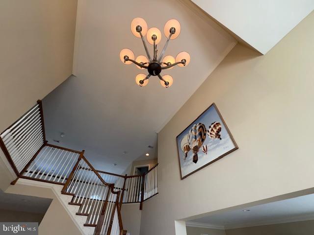 stairway with an inviting chandelier and crown molding