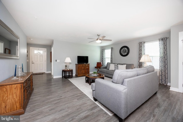 living room featuring dark wood-type flooring and ceiling fan