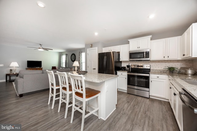 kitchen with appliances with stainless steel finishes, a kitchen breakfast bar, and white cabinets