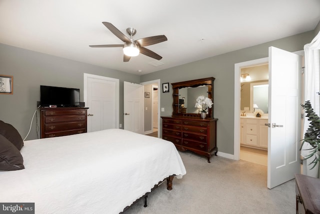 bedroom featuring light colored carpet, ceiling fan, and ensuite bathroom