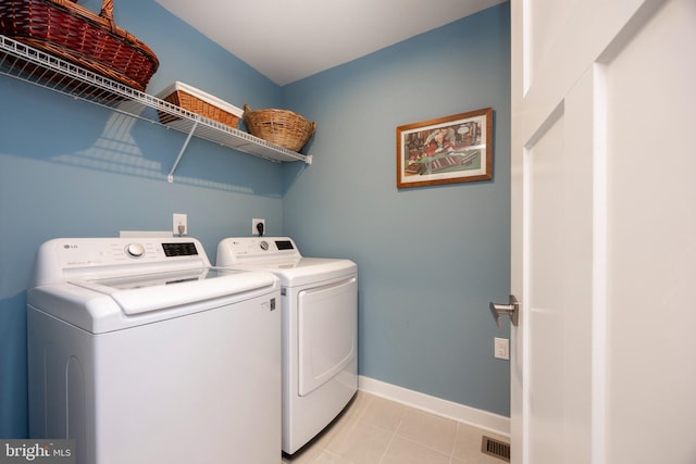 washroom with washing machine and dryer and light tile patterned floors