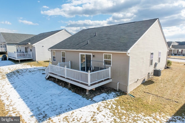 snow covered back of property with central AC, a wooden deck, and a lawn