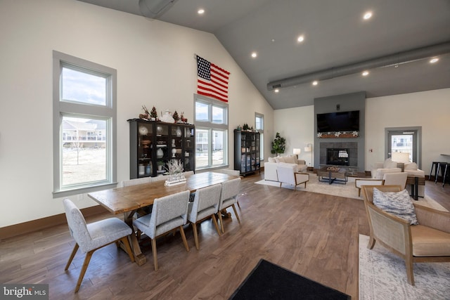 dining room with hardwood / wood-style flooring, a healthy amount of sunlight, and a tile fireplace