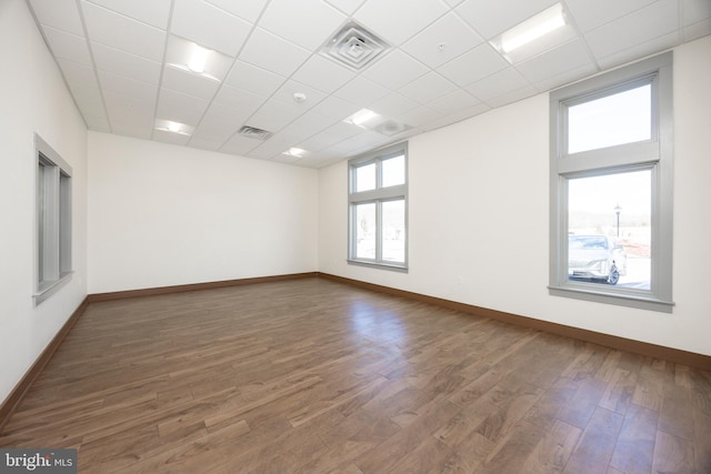 unfurnished room featuring dark hardwood / wood-style floors and a drop ceiling