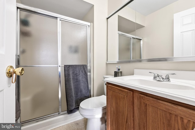 bathroom featuring tile patterned flooring, vanity, a shower with door, and toilet