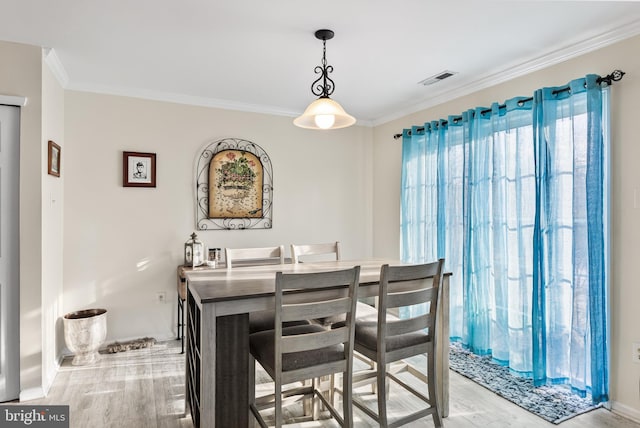 dining room with light hardwood / wood-style flooring and ornamental molding