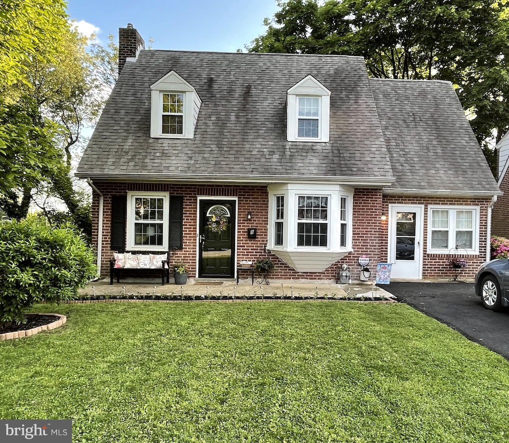 cape cod home with covered porch and a front lawn