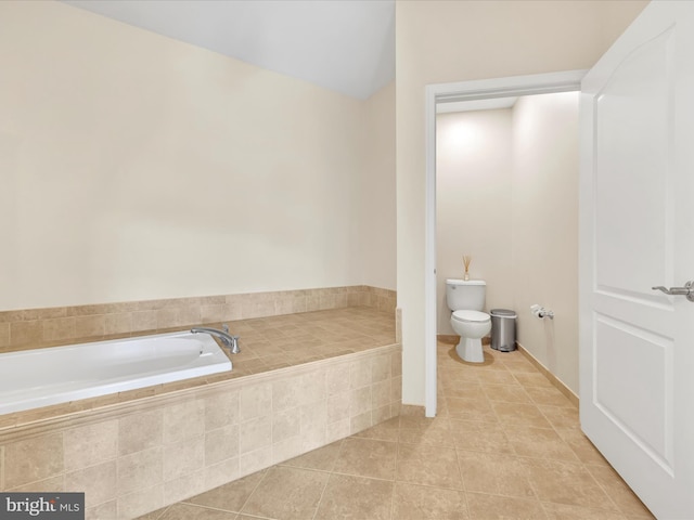 bathroom with tiled bath, tile patterned floors, and toilet