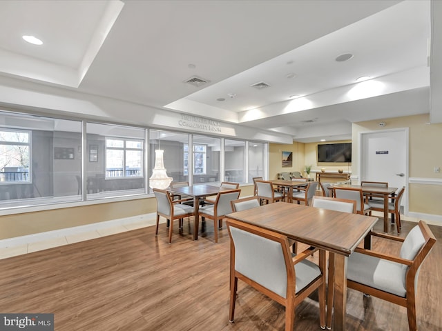 dining space featuring hardwood / wood-style floors and a raised ceiling