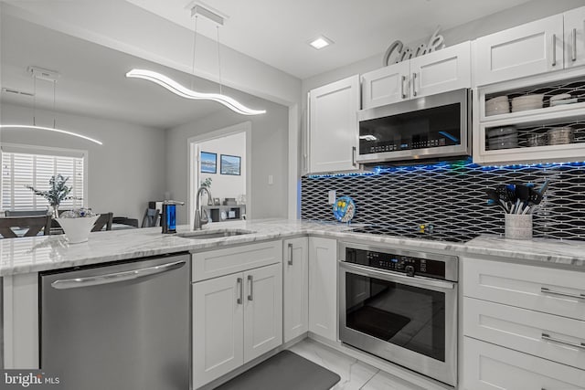 kitchen with sink, white cabinetry, tasteful backsplash, decorative light fixtures, and stainless steel appliances