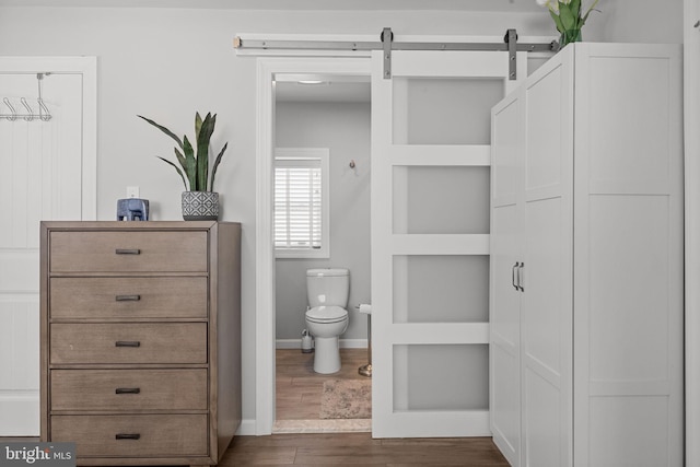 bathroom with hardwood / wood-style flooring, built in features, and toilet