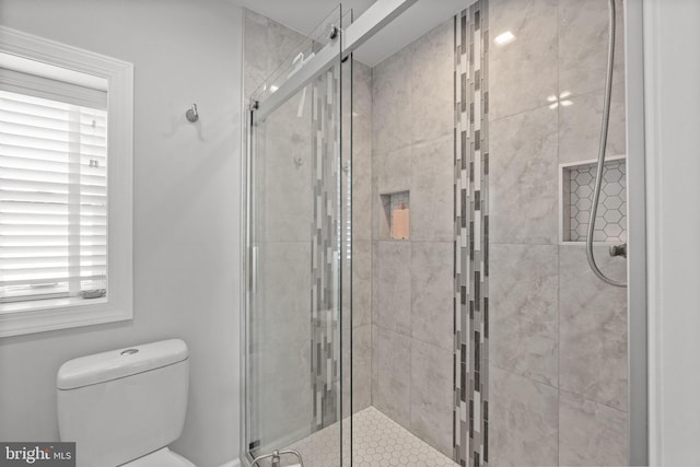 bathroom featuring toilet and a shower with shower door