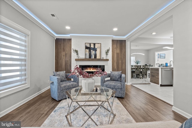 living room with hardwood / wood-style flooring, a fireplace, and ornamental molding