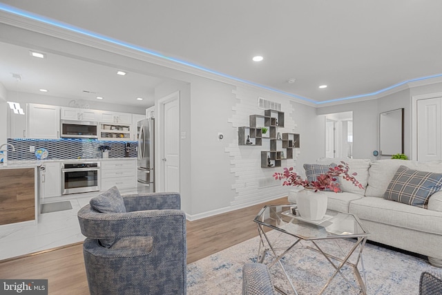 living room with ornamental molding and light hardwood / wood-style flooring