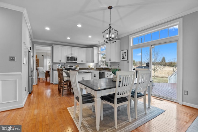 dining space with a notable chandelier, crown molding, light hardwood / wood-style floors, and sink