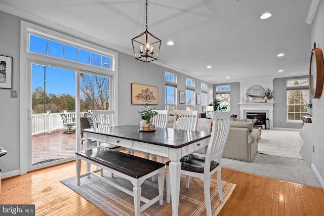 dining space with ornamental molding, a notable chandelier, and light hardwood / wood-style floors