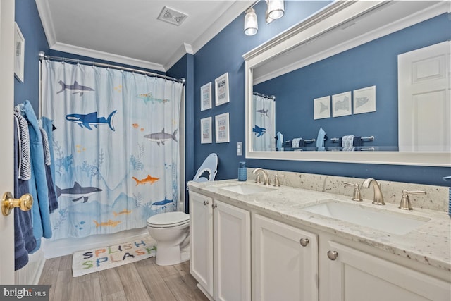 full bathroom featuring shower / tub combo with curtain, hardwood / wood-style floors, vanity, ornamental molding, and toilet