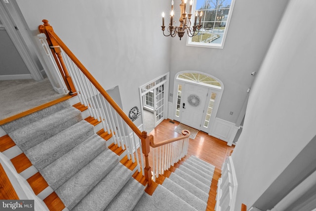 foyer entrance featuring wood-type flooring, a chandelier, and a high ceiling