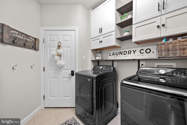 laundry room featuring cabinets, light tile patterned flooring, and washing machine and clothes dryer